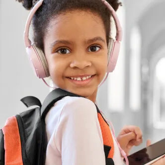 Petite fille souriante portant un casque audio et un sac à dos