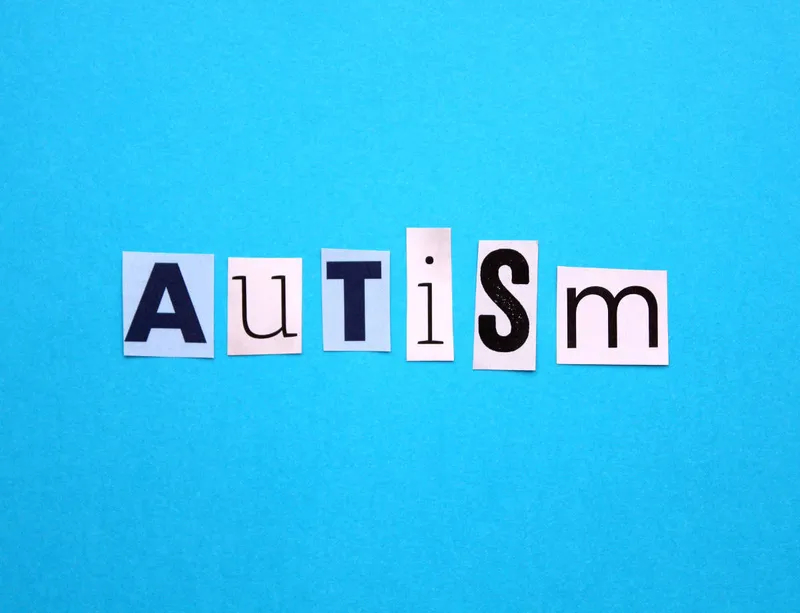 Le mot autism composé en lettres découpées sur fond bleu